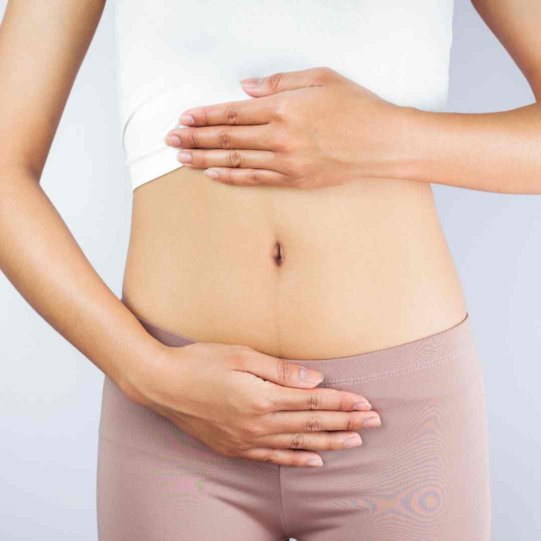 Woman placing hands on abdomen to show focus on women's health.
